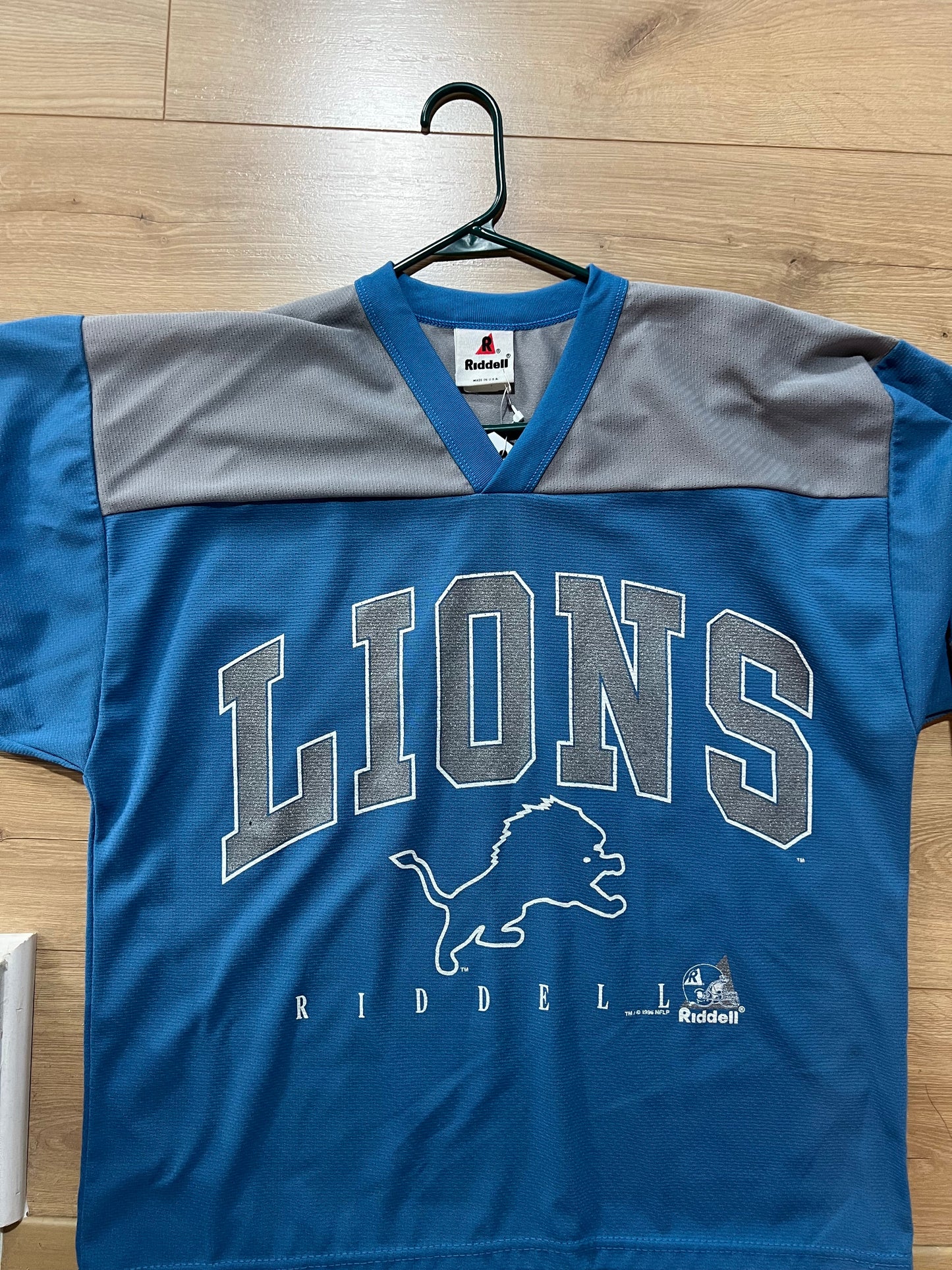 Blue and gray sports jersey with 'Lions' text on a wooden floor